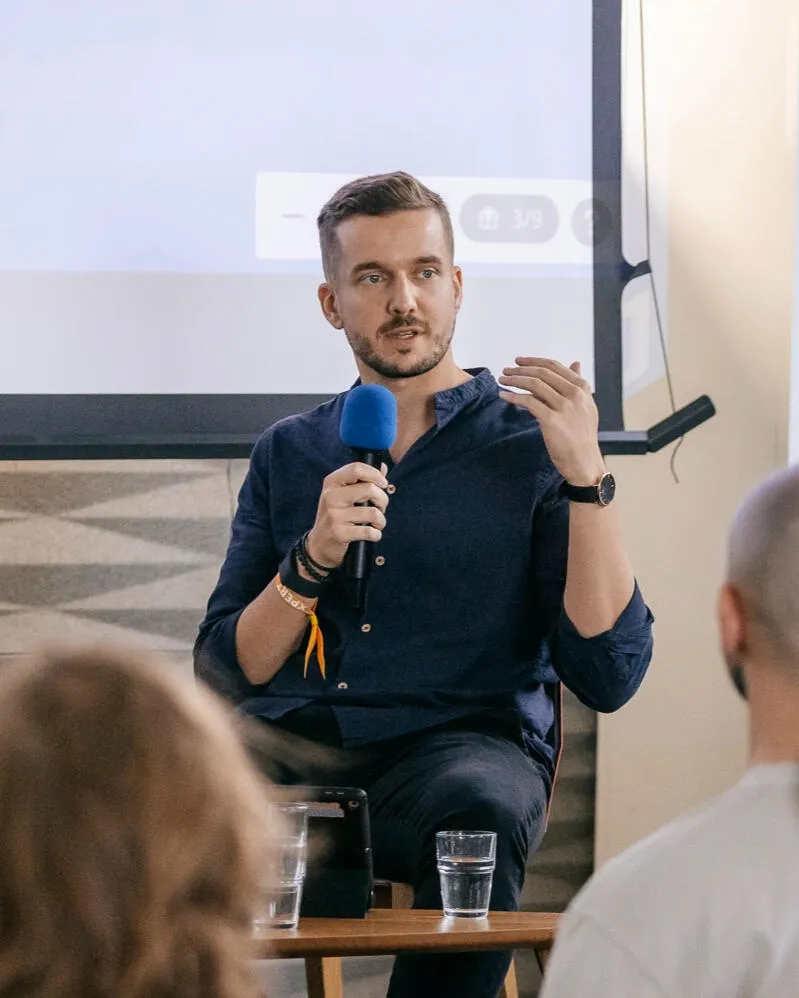 Olek Uznański speaking at a product event, holding a microphone